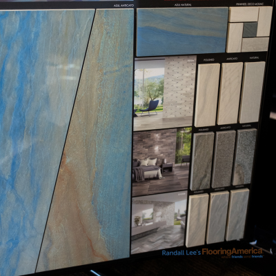 Display board showcasing Azul tile collection with blue and beige slabs, mosaic samples, and room scene photos for inspiration.